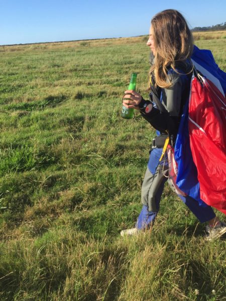 Luci Martyn walking in from a skydive with an Icarus canopy and a beer