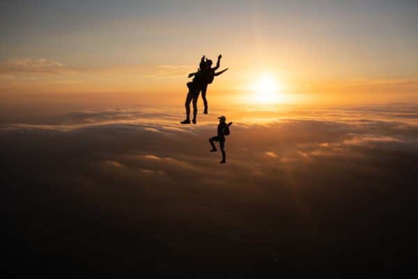 skydivers flying head up in the sunset