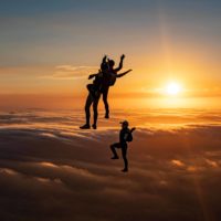 skydivers flying head up in the sunset
