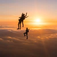 skydivers flying head up in the sunset
