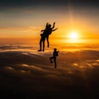 skydivers flying head up in the sunset