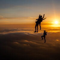 skydivers flying head up in the sunset