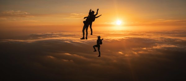 skydivers flying head up in the sunset