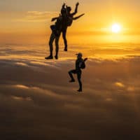 skydivers flying head up in the sunset