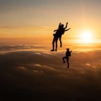 skydivers flying head up in the sunset