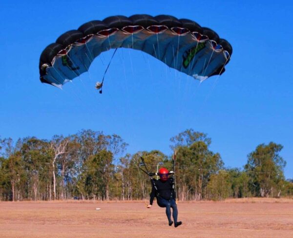 Shane Turner landing his NZ Aerosports Crossfire 3 into a sandy area with a powerful flare