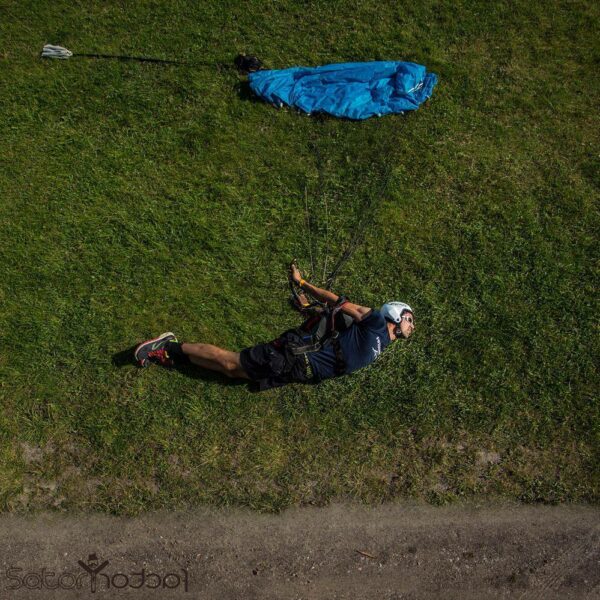 skydiver lying in swooping position on grass with canopy laid out as if flying through air