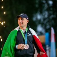 francesco italia smiling holding medal with italian flag draped over shoulders