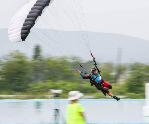 francesco italia swooping icarus petra over pond with blurred background holding rear risers