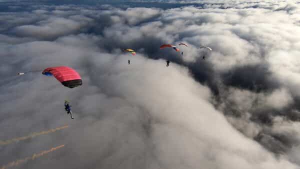 icarus canopies flocking over cloud with smoke streamer
