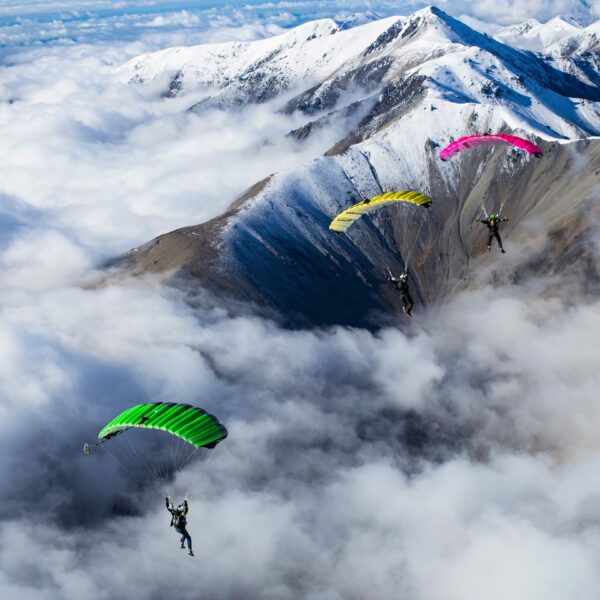 3 green yellow and pink crossfire flying over snow covered mountains