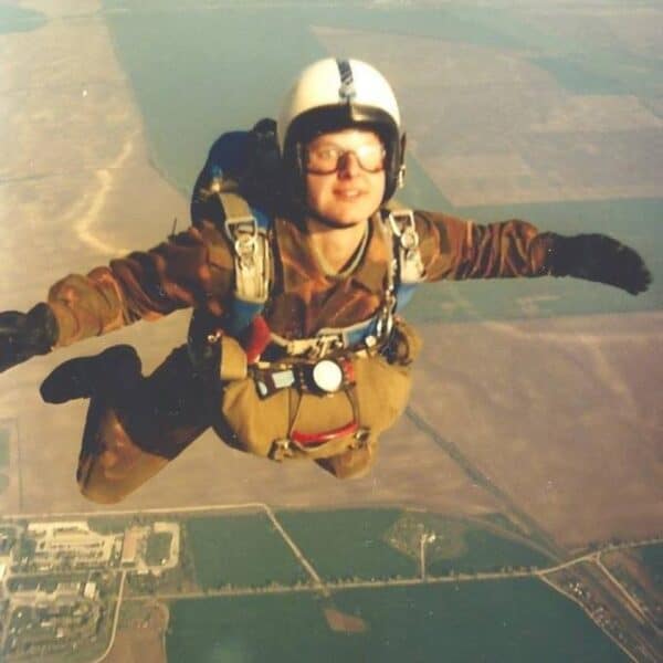 attila wearing white helmet and goggles with front mounted reserve skydive container smiling at camera