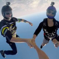 liz peach and mason holden holding hands flying head down in freefall