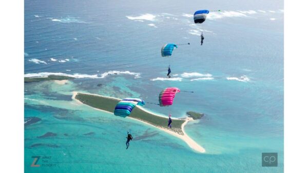 4 canopies flying together with turquoies ocean in background