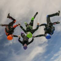 omni99 flying head down holding hands with clouds above them