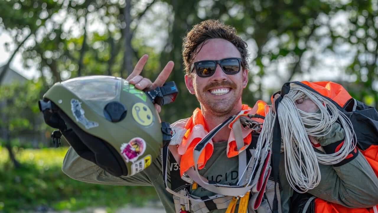 skydiver smiling at camera holding canopy and helmet