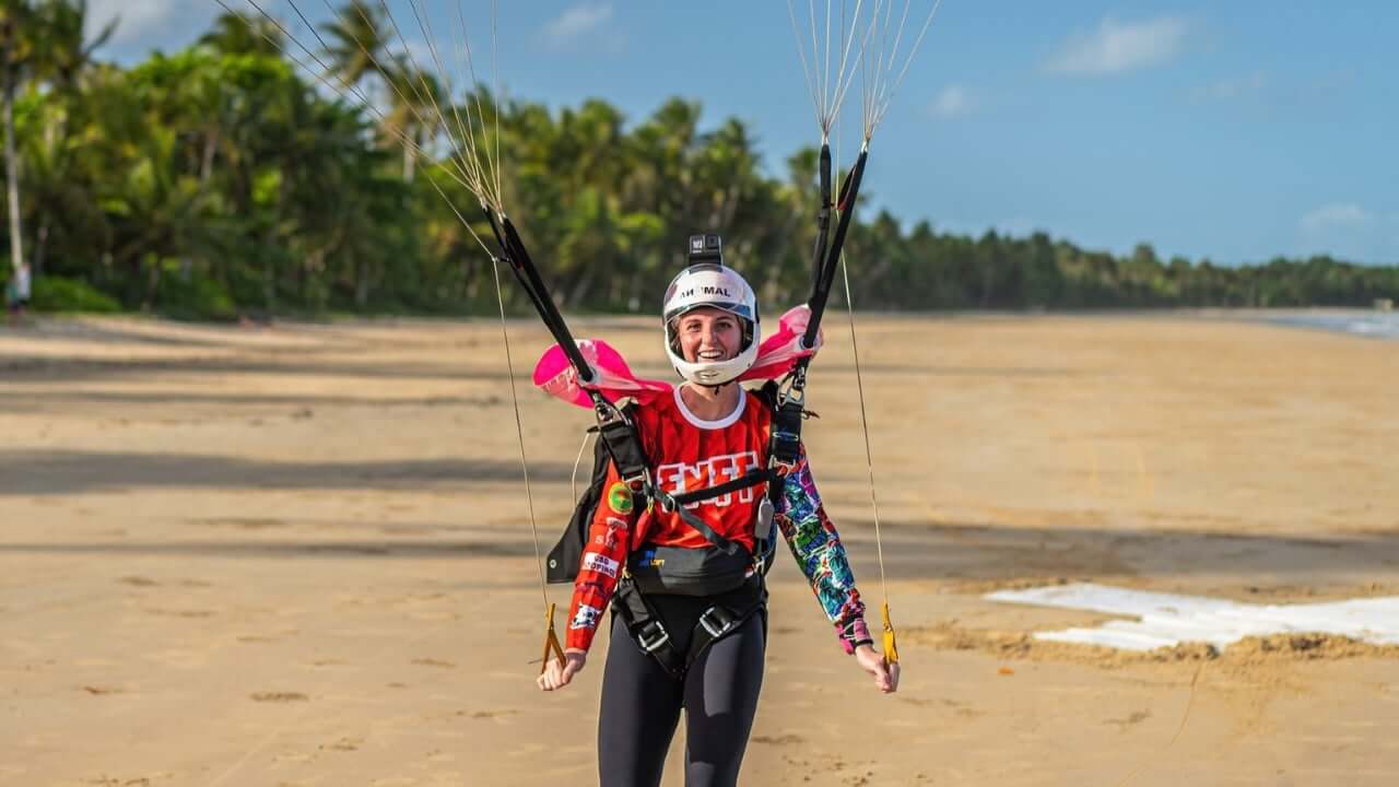 skydiver smiling at camera pulling on toggles with beach in background