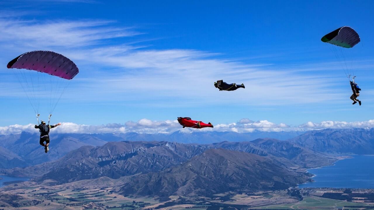 two sleias flying with wingsuiters with mountains in background