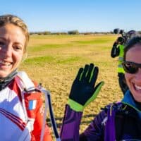 women world record project 19 karine joly smiling at camera with friend on ground after landing from record skydive