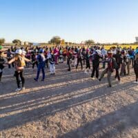 women world record project 19 skydivers holding arms in formation on ground wearing skydive gear with shadows over dirt